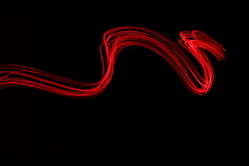 long exposure photograph of neon red colour in an abstract streak pattern against a black background