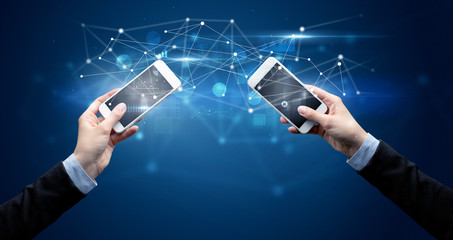 Close up of two hands holding smartphones and sharing business data