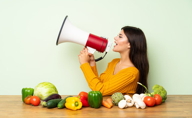 Wall Mural - Teenager girl with many vegetables shouting through a megaphone