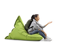 Female Student Sitting On A Green Bean Bag And Gesturing With Hand