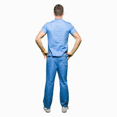 handsome doctor man wearing medical uniform over isolated background standing backwards looking away