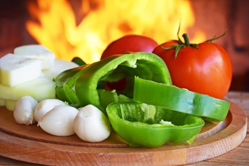 Sliced fresh vegetables for cooking on fire on wooden background.