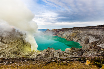 Crater of a volcano with a green sulfuric volcanic lake and volcanic smoke. View of the smoking volcano Kawah Ijen in Indonesia