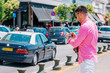 © qunica.com - Stylish tourist calling a lift on his smartphone.