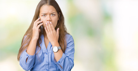 Sticker - Young beautiful brunette business woman talking on smartphone over isolated background cover mouth with hand shocked with shame for mistake, expression of fear, scared in silence, secret concept