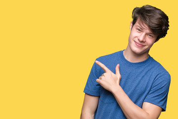 Young handsome man wearing blue t-shirt over isolated background cheerful with a smile of face pointing with hand and finger up to the side with happy and natural expression on face