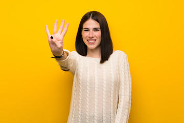 Wall Mural - Young woman over isolated yellow wall happy and counting four with fingers