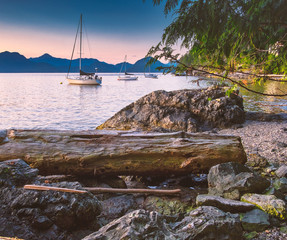 Wall Mural - Sailing and rocky sunset beaches in the pacific north west with a lighthouse guiding the way through the Salish sea to Vancouver British Columbia Canada.