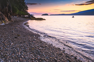 Wall Mural - Sailing and rocky sunset beaches in the pacific north west with a lighthouse guiding the way through the Salish sea to Vancouver British Columbia Canada.