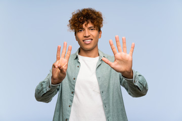 Wall Mural - Young african american man over isolated blue wall counting eight with fingers