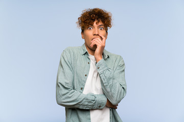 Wall Mural - Young african american man over isolated blue wall surprised and shocked while looking right