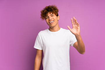 Wall Mural - Young african american man over isolated purple wall saluting with hand with happy expression