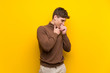 © luismolinero - Handsome young man over isolated yellow background is suffering with cough and feeling bad