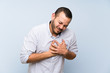 © luismolinero - Colombian man over isolated blue wall having a pain in the heart