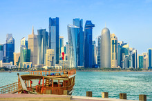 Traditional Wooden Dhow On Foreground At Doha Bay And Skyscrapers Towers Of West Bay Skyline On Background. Capital Of Qatar, Middle East, Persian Gulf. Sunny Blue Sky. Urban Modern Cityscape.