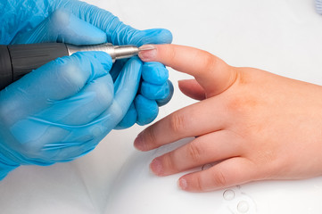 Wall Mural - Woman use electric nail file drill in beauty salon. Perfect nails manicure process or operation in close up.