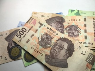 Mexican peso bills spread over white background