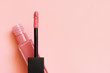 © Kat Ka - Liquid lipstick and applicator on coral pink color background. Open tube of lip gloss and wand brush with makeup product on pastel coral surface. Top view, flat lay, copy space