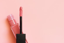 Liquid Lipstick And Applicator On Coral Pink Color Background. Open Tube Of Lip Gloss And Wand Brush With Makeup Product On Pastel Coral Surface. Top View, Flat Lay, Copy Space