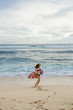 © Sibstock/Stocksy - Back view: woman in swimwear walk on the beach