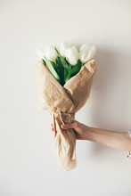 Female Hand Holding Tulip Bouquet In Front Of A White Background