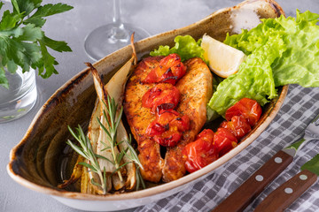 Wall Mural - Baked salmon fillet with tomatoes and stern celery on a plate. Diet food. Closeup