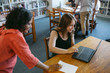 © Rob and Julia Campbell/Stocksy - Teacher helping student on computer in library study room