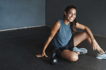 Active lifestyle and sport concept. Happy gorgeous fit sportswoman wear sportswear, motivated good training fitness session, rest on gym floor, workout kettlebell squats, smile camera pleased