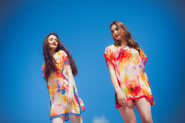 Wall Mural - Two gorgeous young women wearing swimmwear, against the blue sky