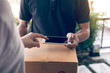© wutzkoh - Close up of hand asian man using smartphone pressing screen to sign for delivery from the courier at home.