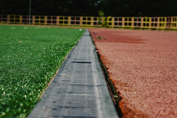 jogging track with metal grating and green grass.