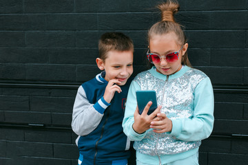 Wall Mural - Little boy and girl playing game on mobile phone together