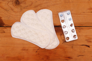 Menstrual pad and blue pills on wood table, women critical days, Gynecological menstruation cycle 