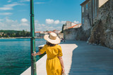 Fototapeta Dziecięca - woman walking by sea quay in summer day in yellow sundress