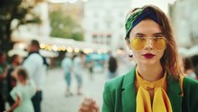 Street Fashion Close Up Portrait Of Young Beautiful Elegant Lady Wearing Trendy Yellow Color Sunglasses, Headband, Stylish Blouse, Green Blazer, Posing In Old European City