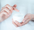 © Artem Markin - Female tattooed hands holding a jar of cream. Finger with a drop of white cream
