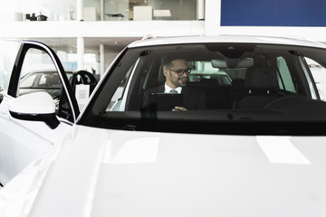 Poster - Car seller working in showroom and quality control checking of car details for the last time before buyer comes.