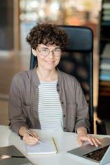 Poster - Happy brunette girl writing down her ideas on page of notebook