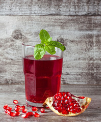 A glass of pomegranate juice with fresh pomegranate fruits on wooden table. Vitamins and minerals. Healthy drink concept.