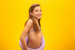 Child wearing bikini on yellow background. Concept of summer, beach and pool.