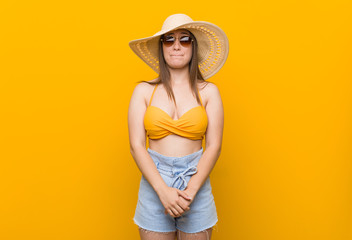 Young caucasian woman wearing a straw hat, summer look confused, feels doubtful and unsure.