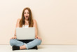 © Asier - Young ginger woman sitting on her house floor being shocked because of something she has seen.