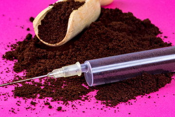 Coffee powder on pink background with syringe of pure caffeine