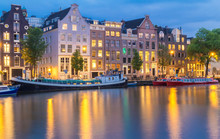 Night City View Of Amsterdam Canal, Typical Dutch Houses And Boats, Holland, Netherlands.