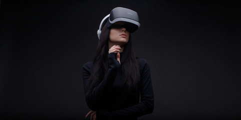 Beautiful woman over dark background. Girl in glasses of virtual reality. Augmented reality, game, hobby concept. VR.