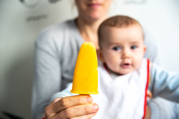 Wall Mural - Orange ice cream in the foreground with baby in the background wishing to catch it.