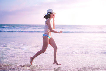 young woman on sunset beach and joyful running . happy summer vacation. positive lifestyle and relaxing travel. nature recreation.