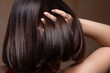 A sexy young Caucasian girl is seen from behind using her fingers to play with her long brown hair. Pulling it up to create a bob style on the back of her head.