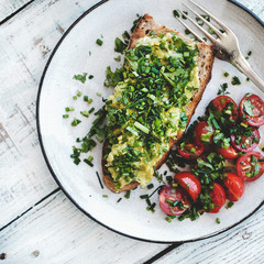 Wall Mural - Healthy lunch. Flat-lay of avocado toast on sourdough bread with chives, coriander, cherry-tomatoes with cup of coffee over white background, top view, square crop. Vegetarian, clean eating concept