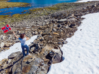 Wall Mural - Tourist holds norwegian flag in mountains